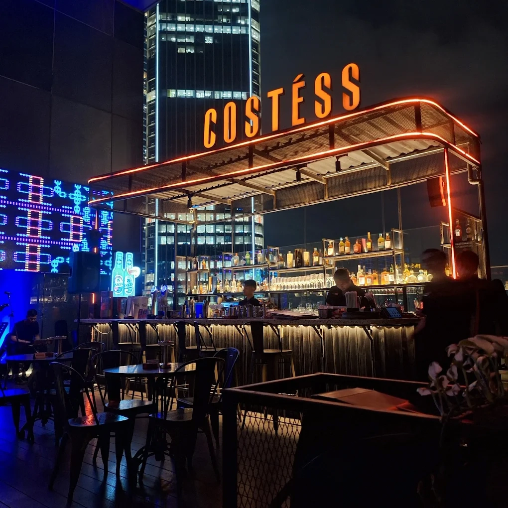 costess rooftop bar with glowing neon sign at night