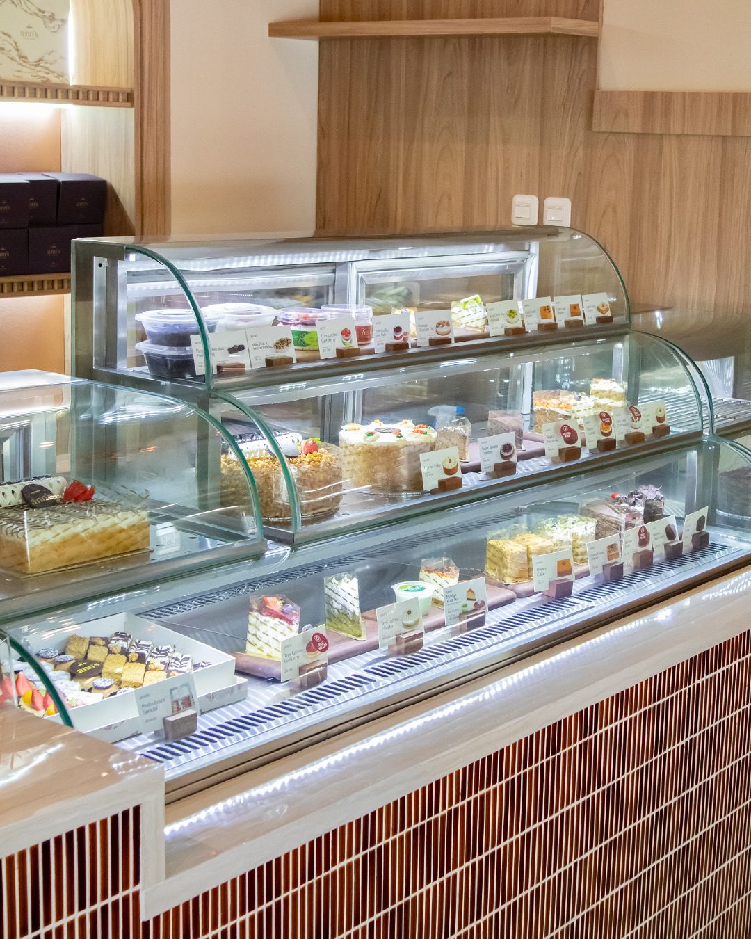 curved glass cake display case filled with sliced cakes and treats