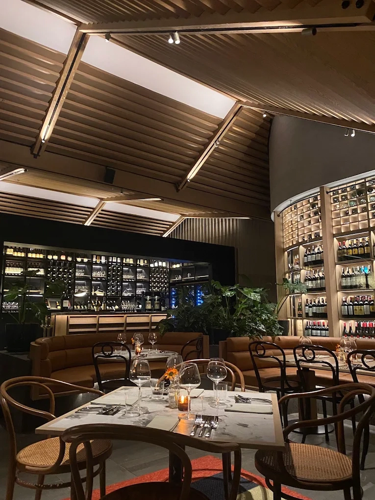 elegant restaurant interior featuring wooden vaulted ceiling and wine display walls