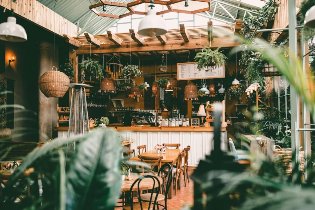 greenhouse-style cafe interior with hanging plants and wooden tables