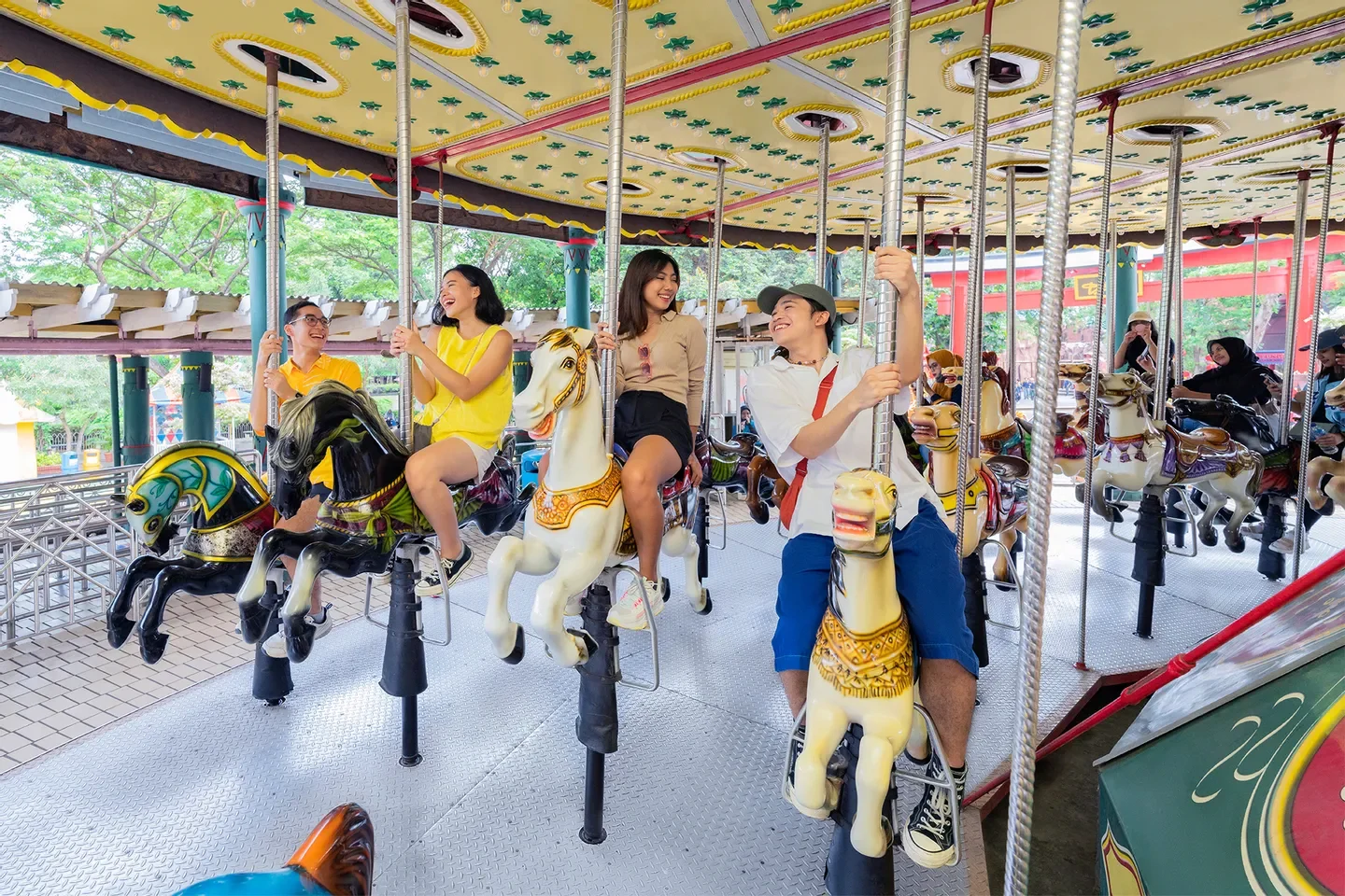 group of friends smiling and riding carousel horses at a park