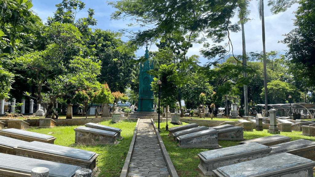 historic cemetery park with stone tombs and a green gothic monument