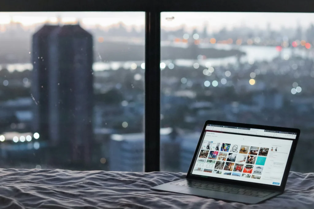 laptop on bed with city lights background