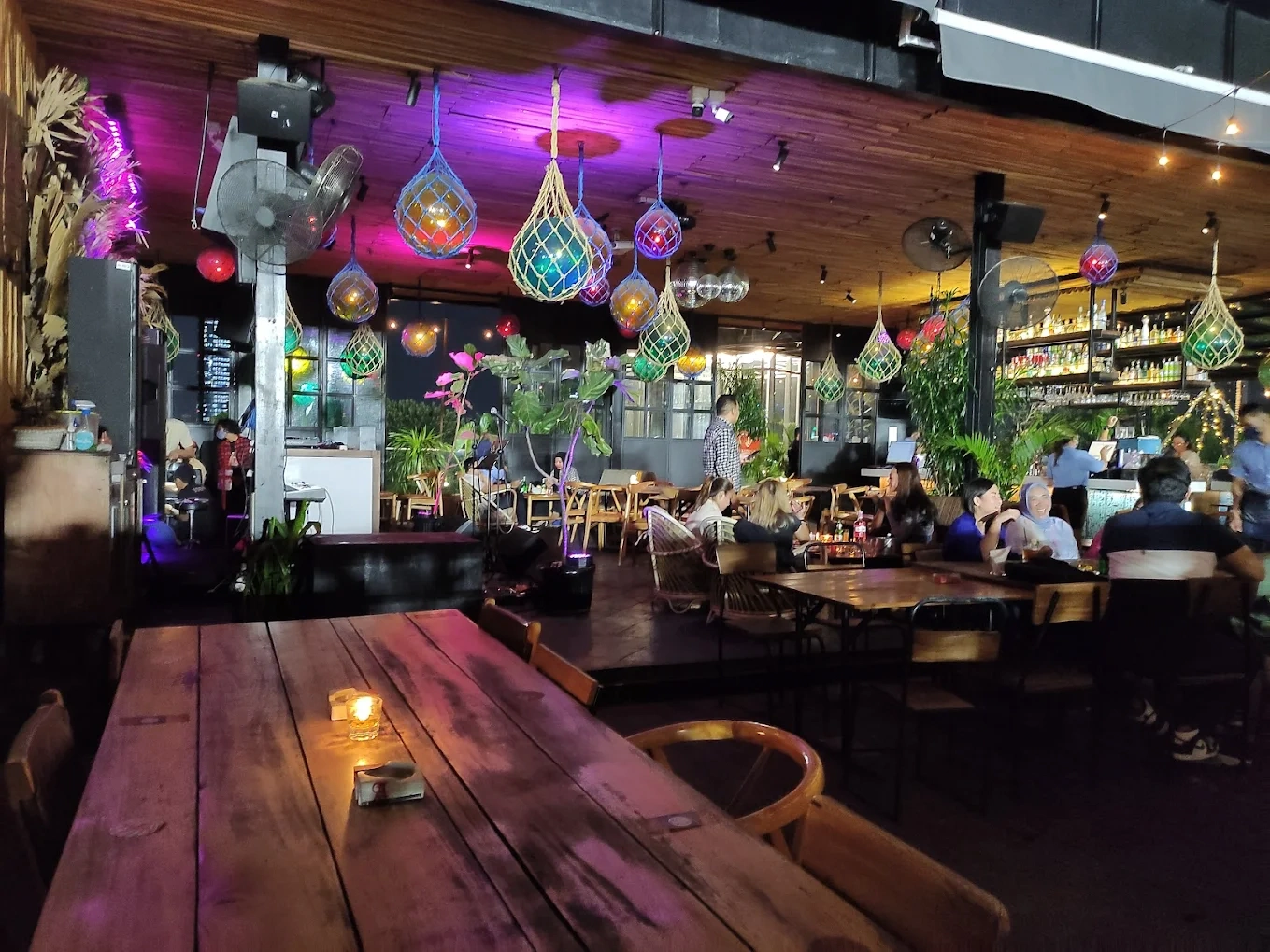 lively indoor venue with colorful woven pendant lights and wooden dining tables
