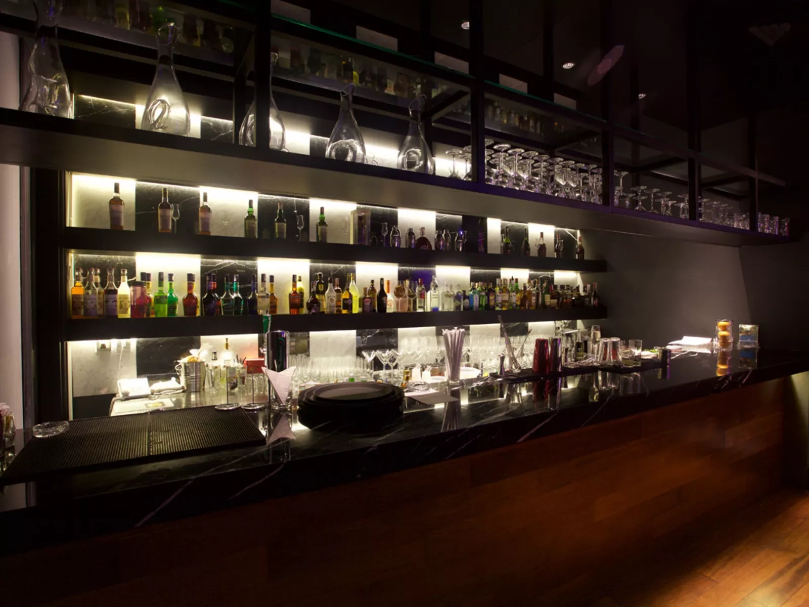 modern bar counter with back-lit liquor bottle shelves