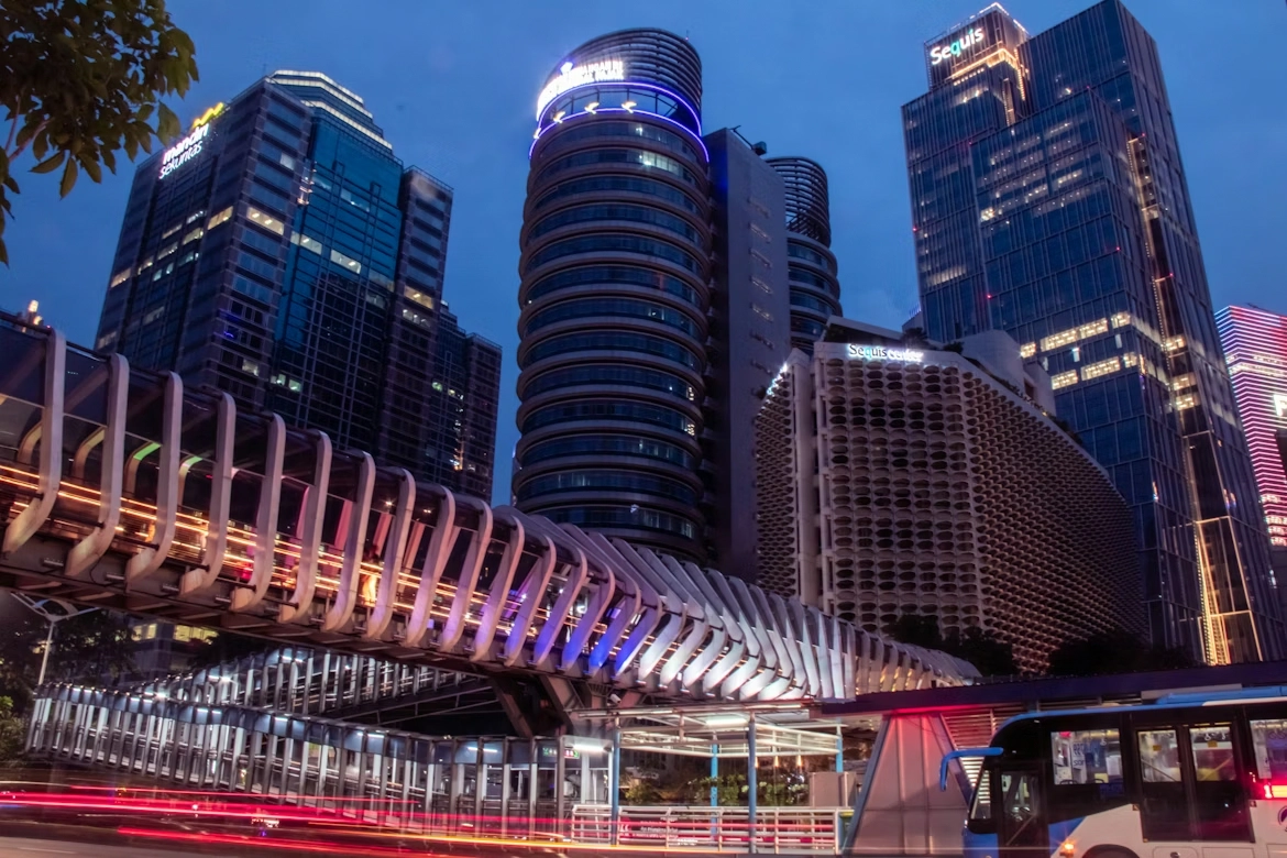 modern pedestrian skywalk lit up at dusk with scbd skyscrapers in background