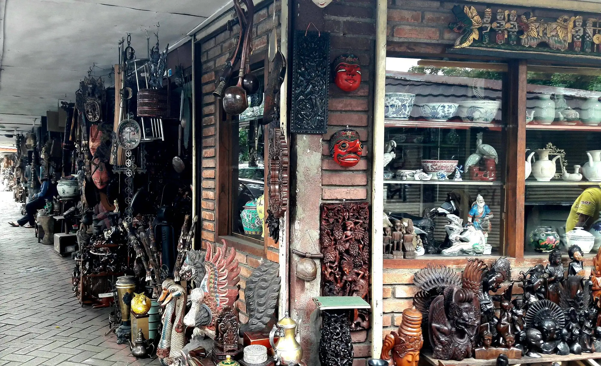 outdoor antique market stall displaying traditional indonesian masks and carvings