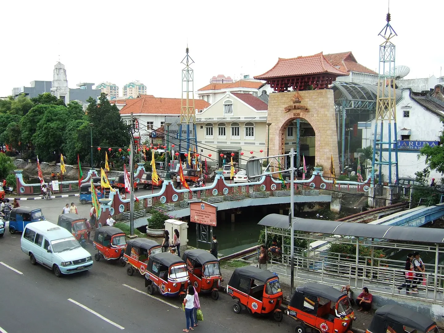 pasar baru gate and bridge with red bajaj vehicles parked along the road