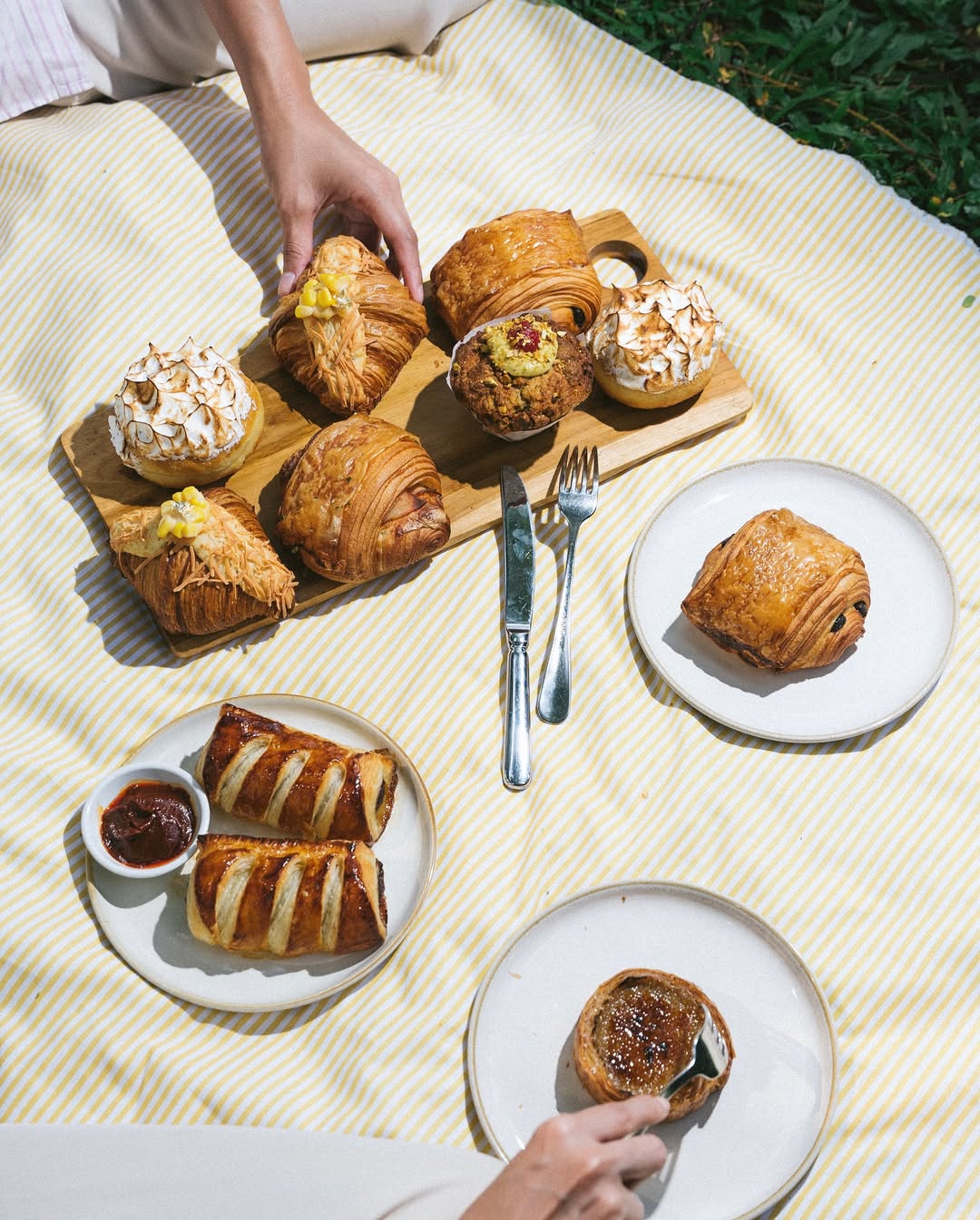 picnic blanket layout with various golden pastries and plates