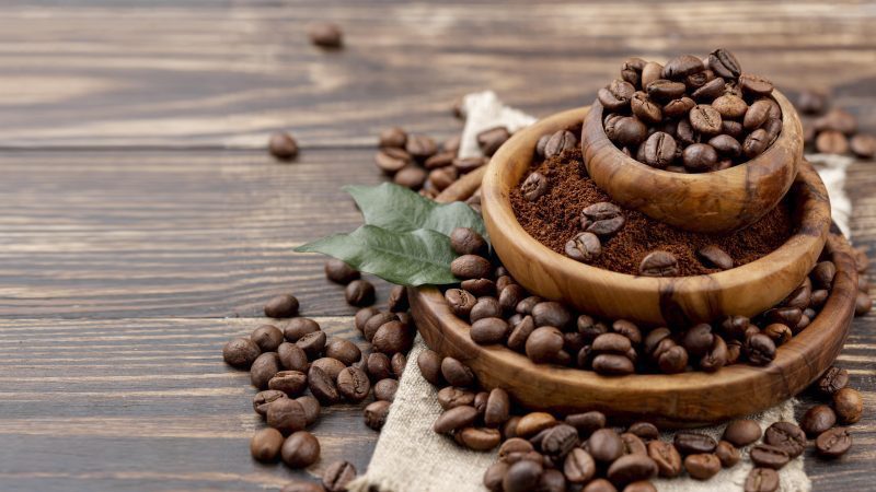 roasted coffee beans and ground coffee in wooden bowls