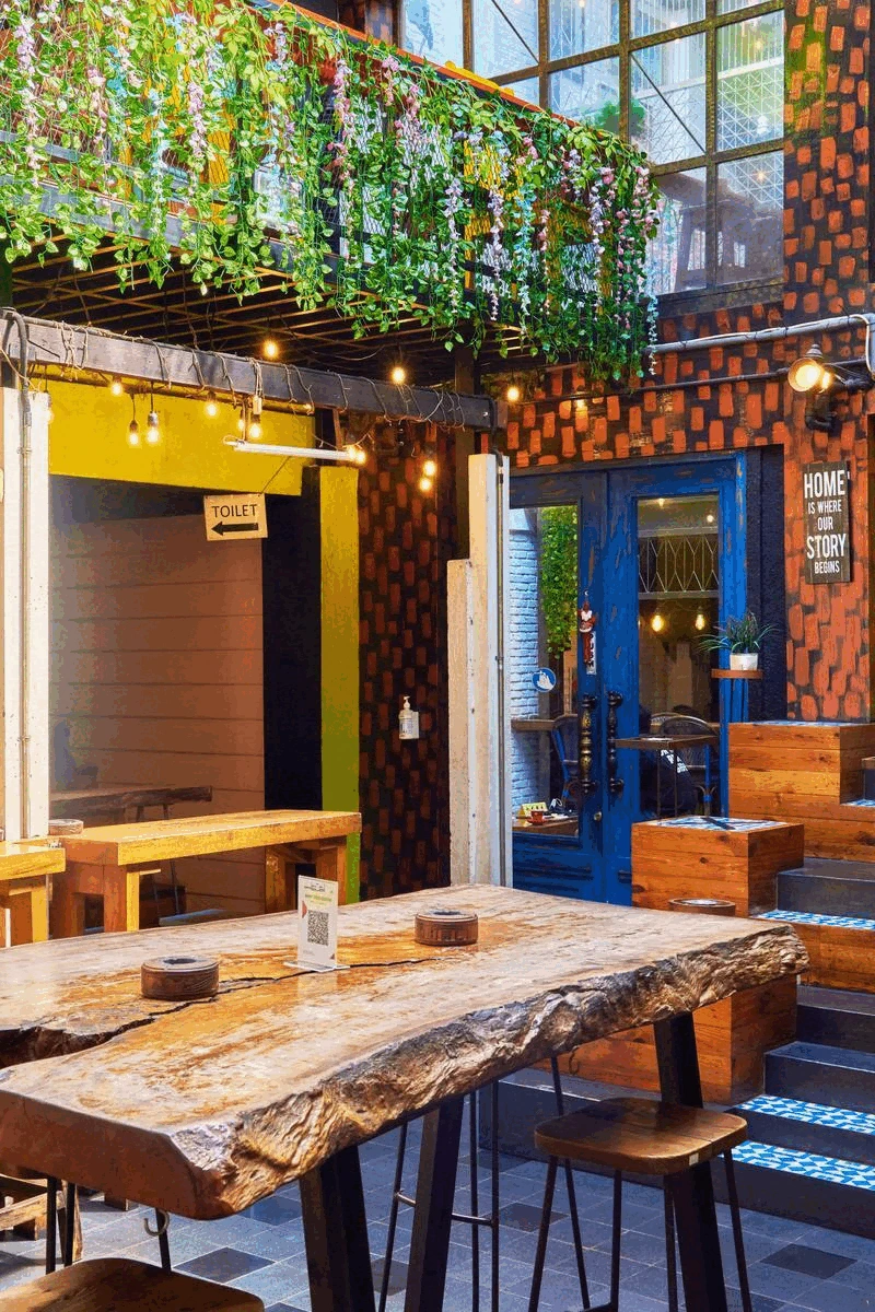 rustic outdoor cafe setting with wooden tables and hanging greenery