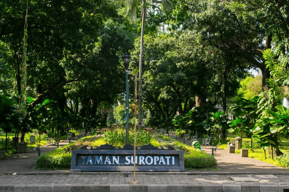 taman suropati park sign with benches in a leafy setting