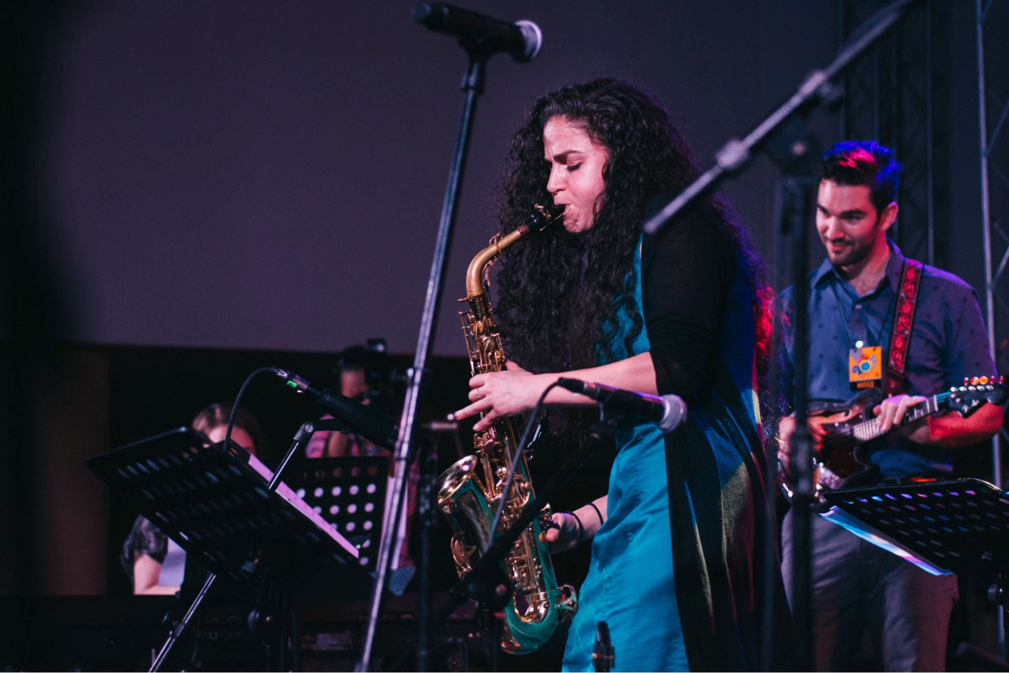 woman playing saxophone live on stage with a band